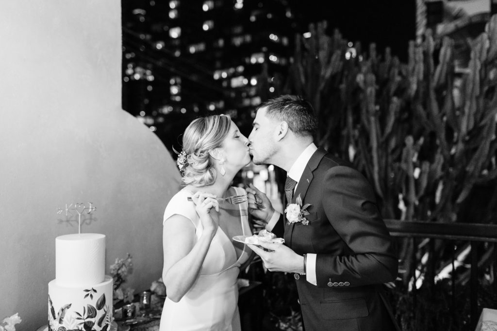 bride and groom kiss while cutting cake at their spring wedding at Hotel Figueroa