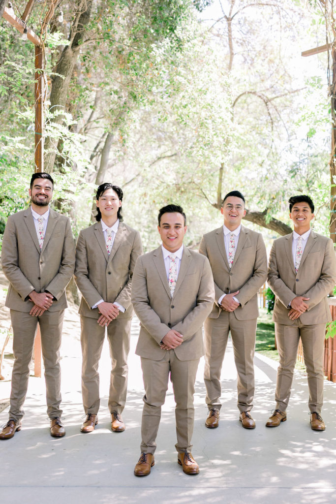 groom and groomsmen wearing tan suit with floral tie