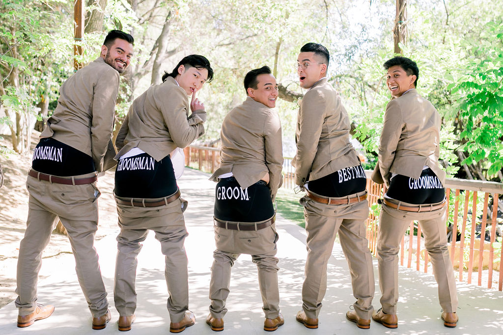 groom and groomsmen wearing tan suit with floral tie show off their customized groomsemen boxers