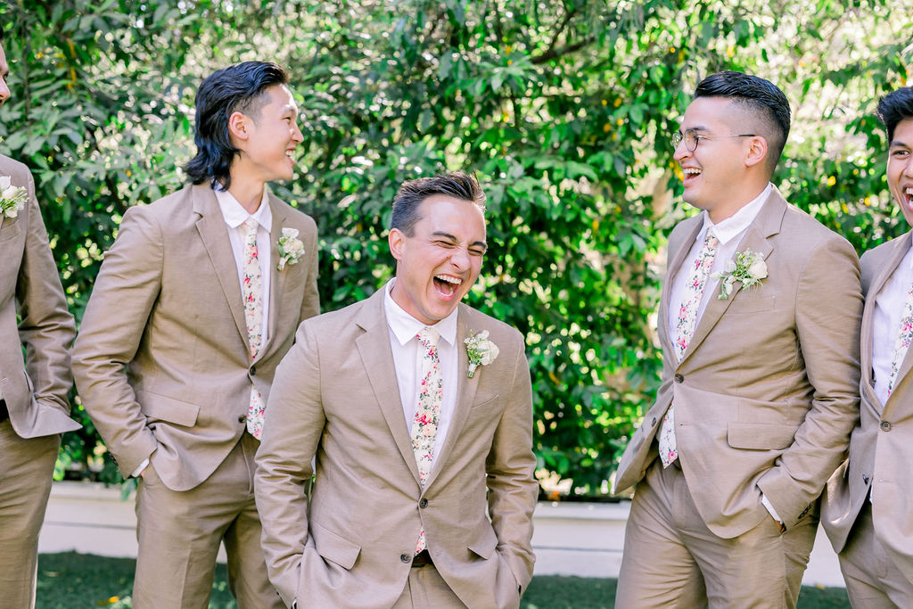 groom standing with groomsmen wearing tan suits and floral ties