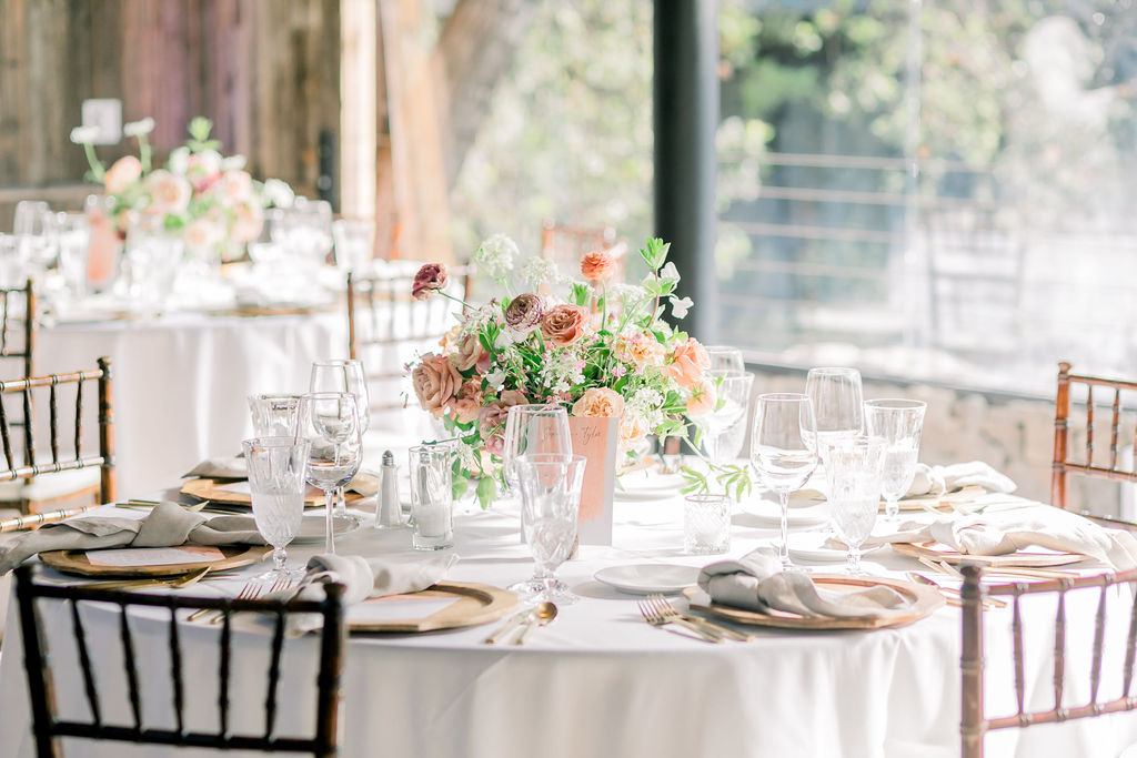 wedding reception tables at the Redwood Room at Calamigos Ranch with pink and orange floral centerpieces