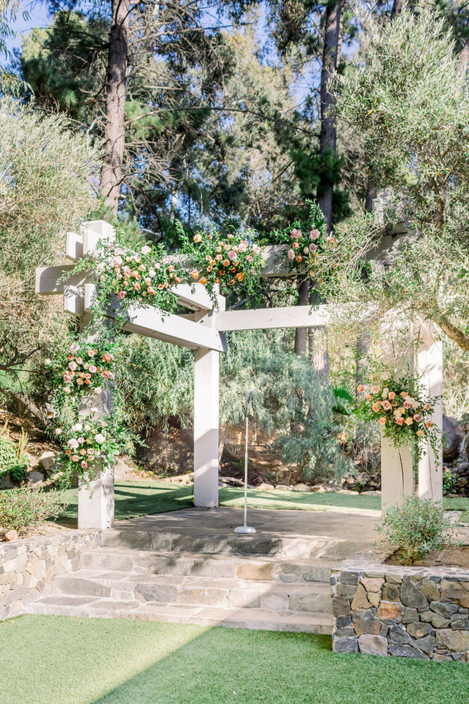 Redwood Room ceremony site at Calamigos Ranch with arch covered in flowers