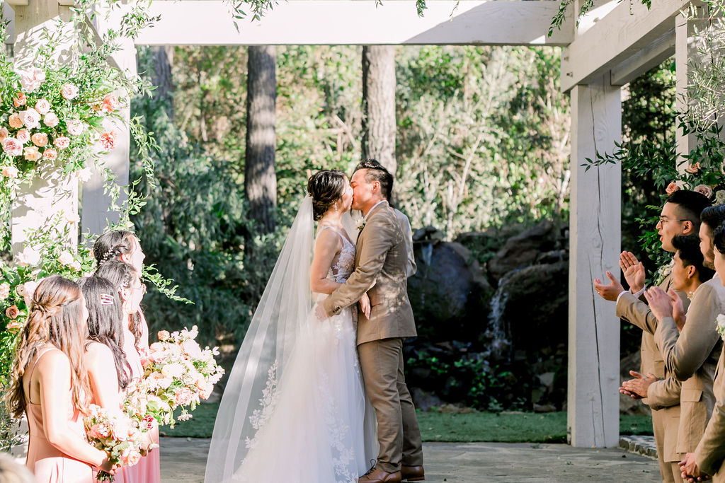 bride and groom share first kiss during their wedding ceremony at the Redwood Room at Calamigos Ranch