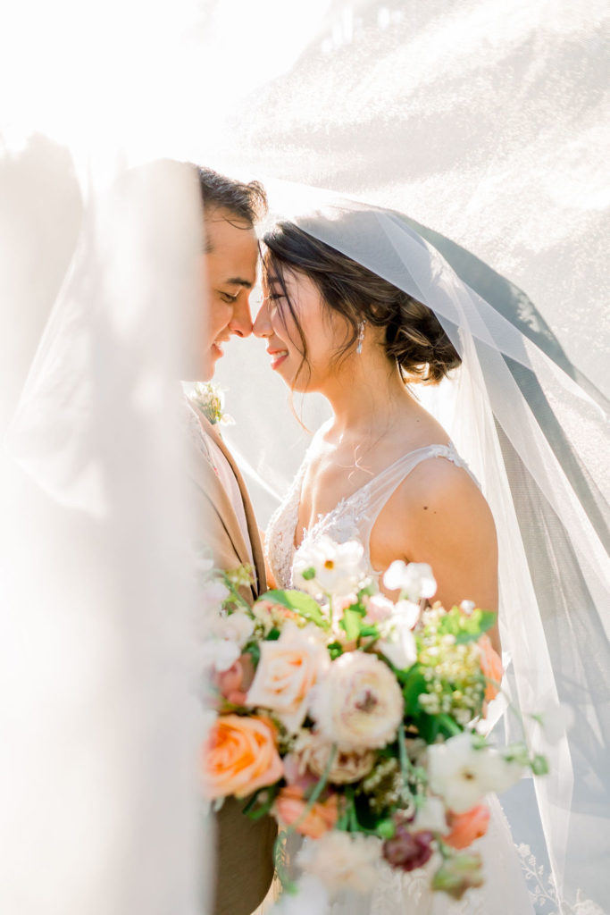 An enchanting wedding at Calamigos Ranch, bride and groom take photos in brides veil