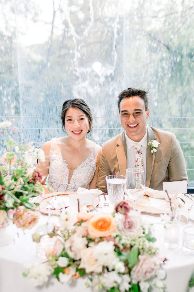 bride and groom sit at sweetheart table during reception dinner