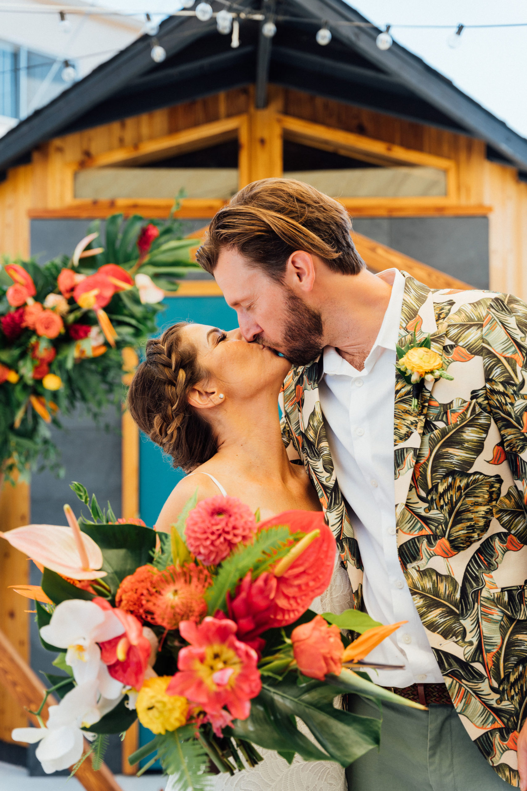 bride and groom kiss in front of tiki bar after backyard wedding ceremony