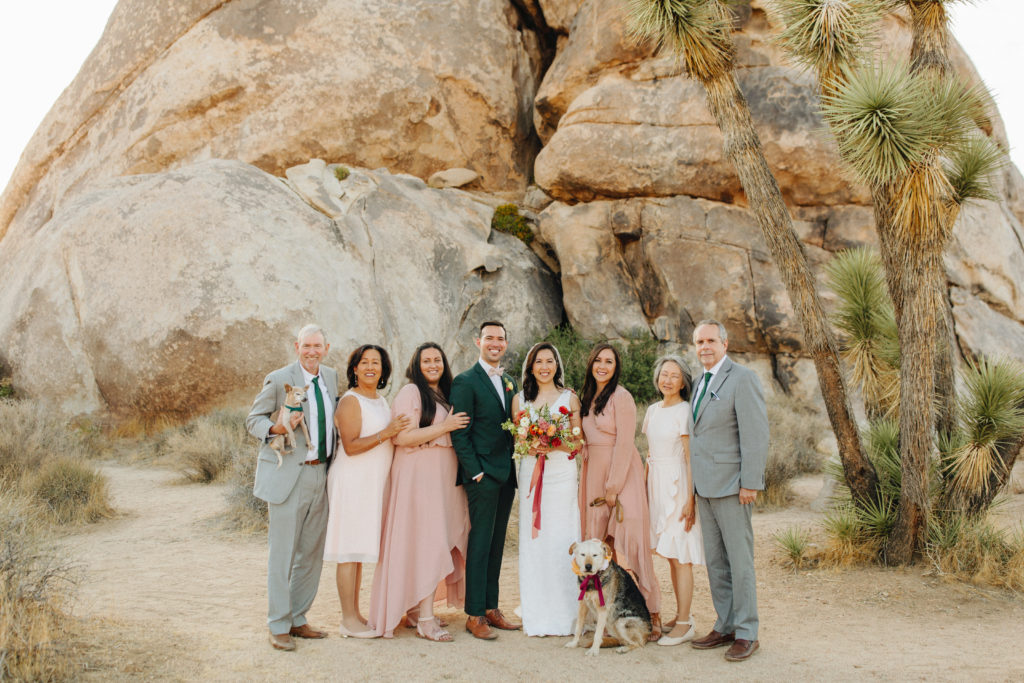 bride and groom family portraits in front of large rocks during desert elopement in Joshua Tree