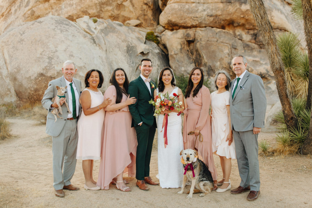 bride and groom family portraits in front of large rocks during desert elopement in Joshua Tree