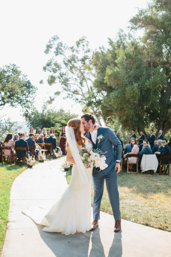 bride and groom kiss at the end of the aisle