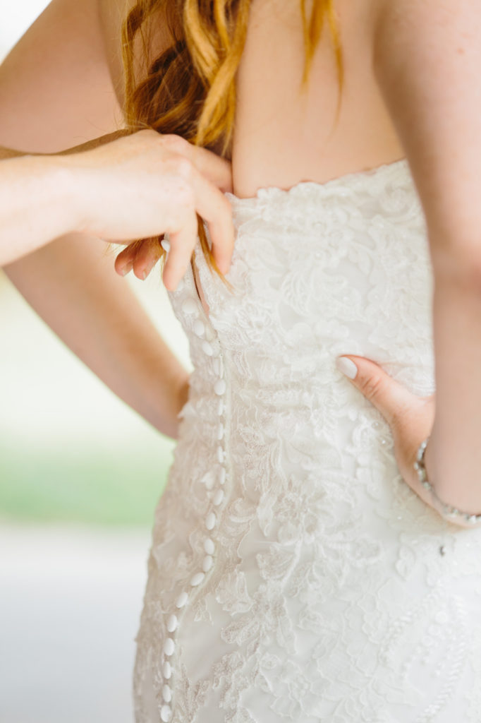 bride getting zipped up in wedding dress