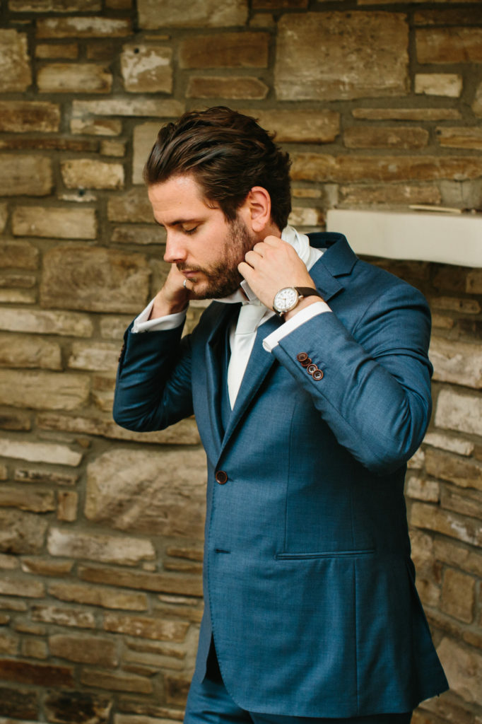groom in blue suit getting ready for wedding day