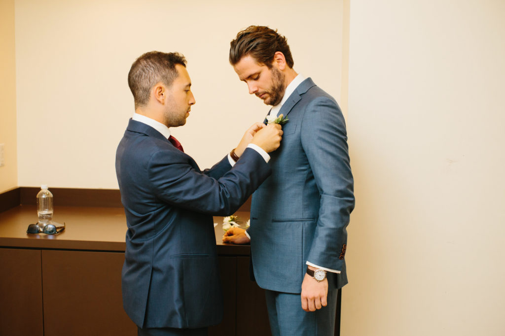 groomsmen helps tie groom's tie before wedding day