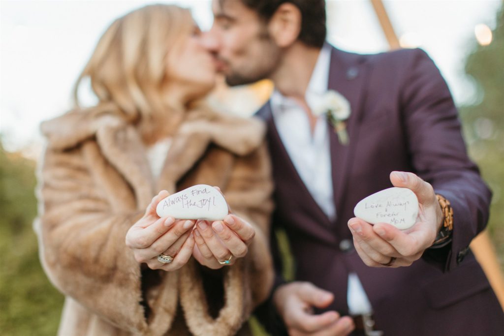 bride and groom hold stones with good luck messages written on them from wedding guests