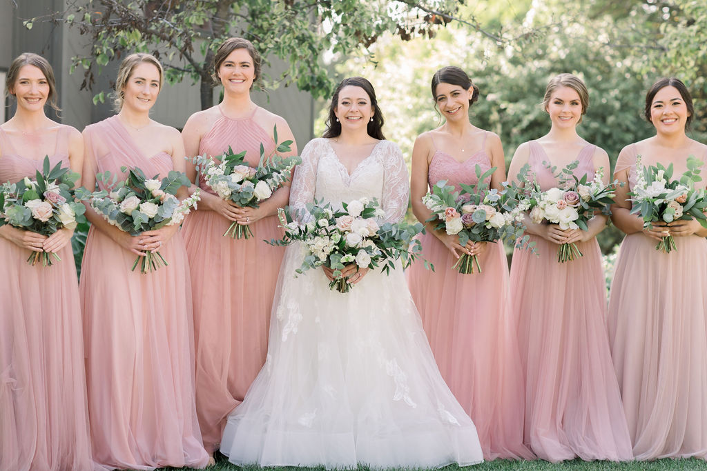 bride in long sleeve wedding dress with bridesmaids in pink bridesmaid dresses