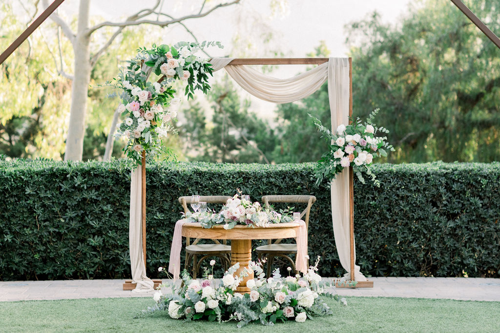 sweetheart table at wedding reception with pink, white and green florals