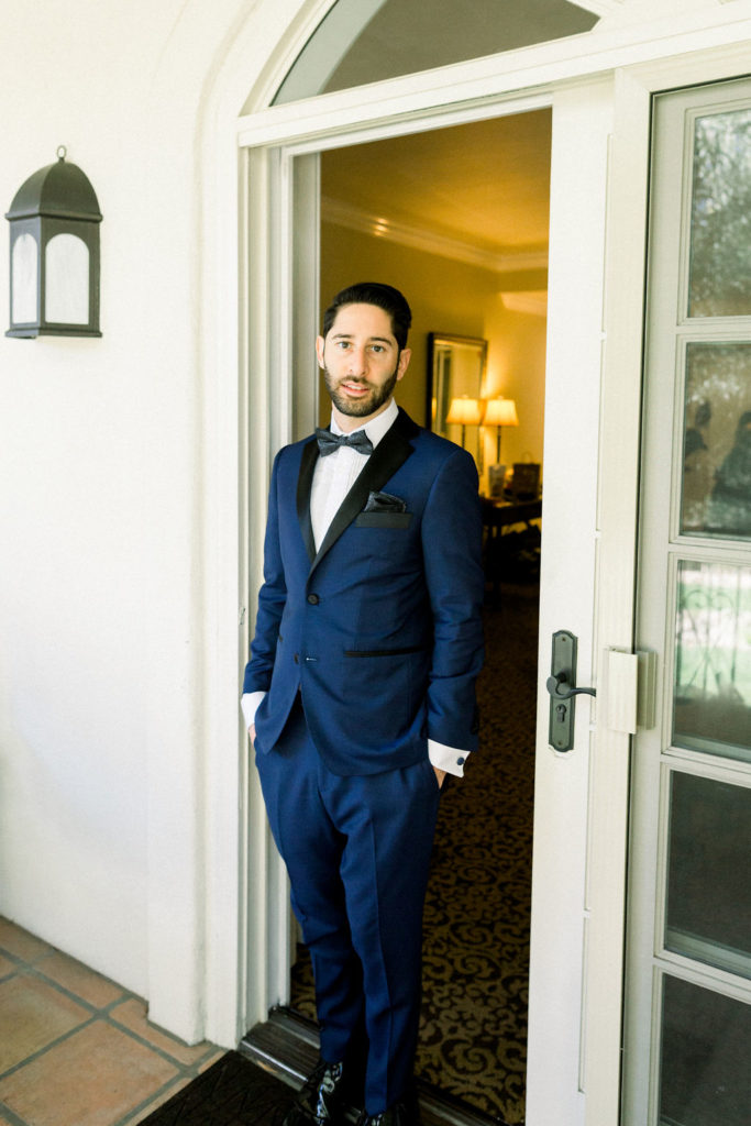 groom in blue suit with black bow tie getting ready for wedding day