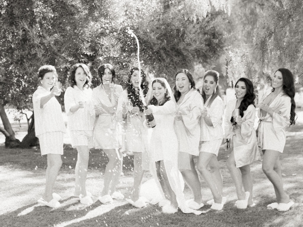 bride opens champagne with bridesmaids in robes