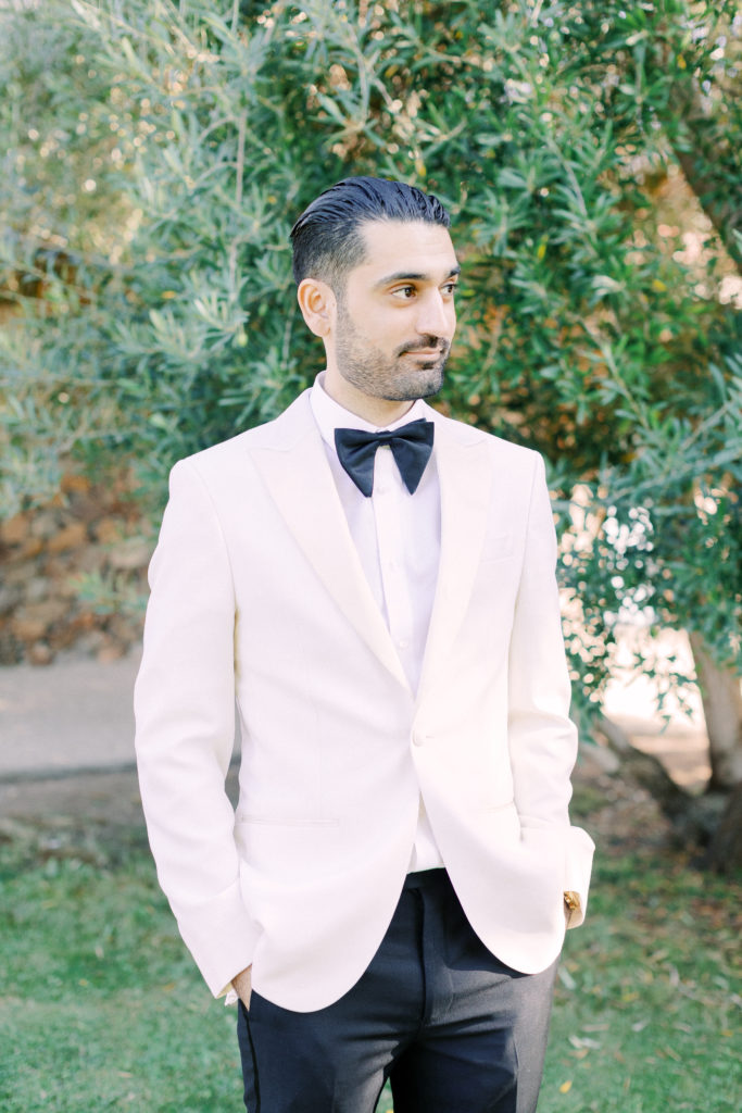 groom in white tuxedo jacket with black bowtie