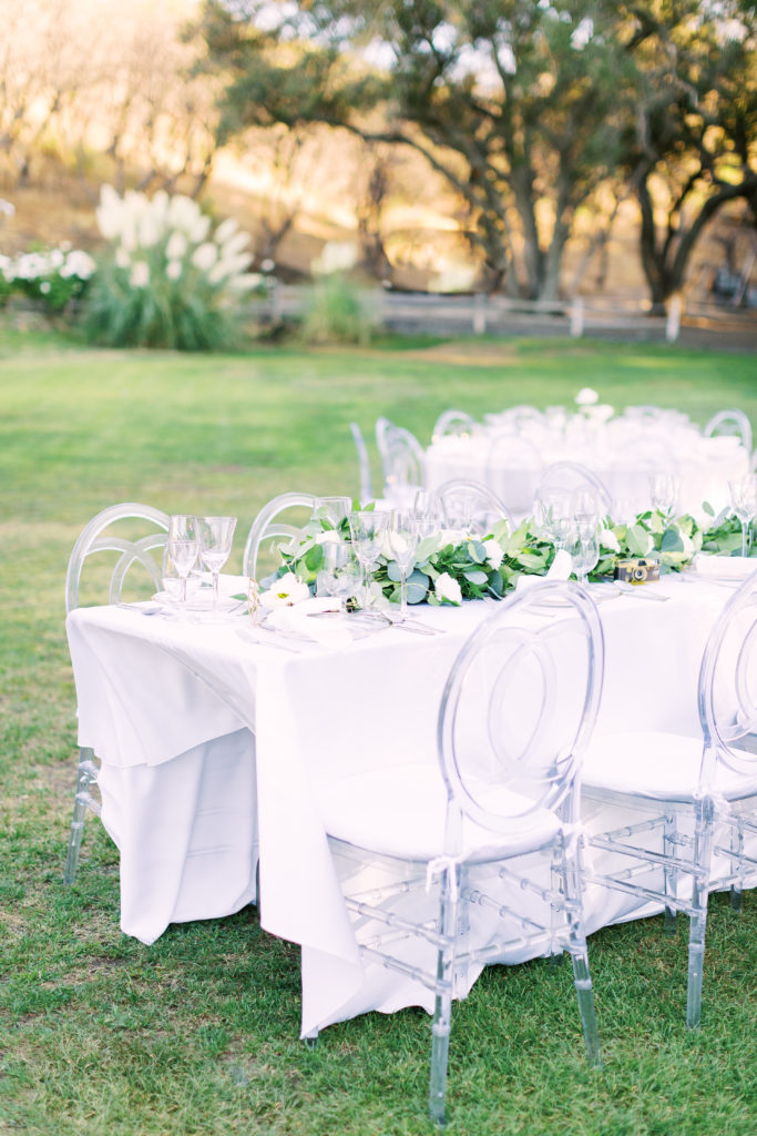 black-tie wedding reception at Saddlerock Ranch with clear reception chairs and all white rose floral centerpieces