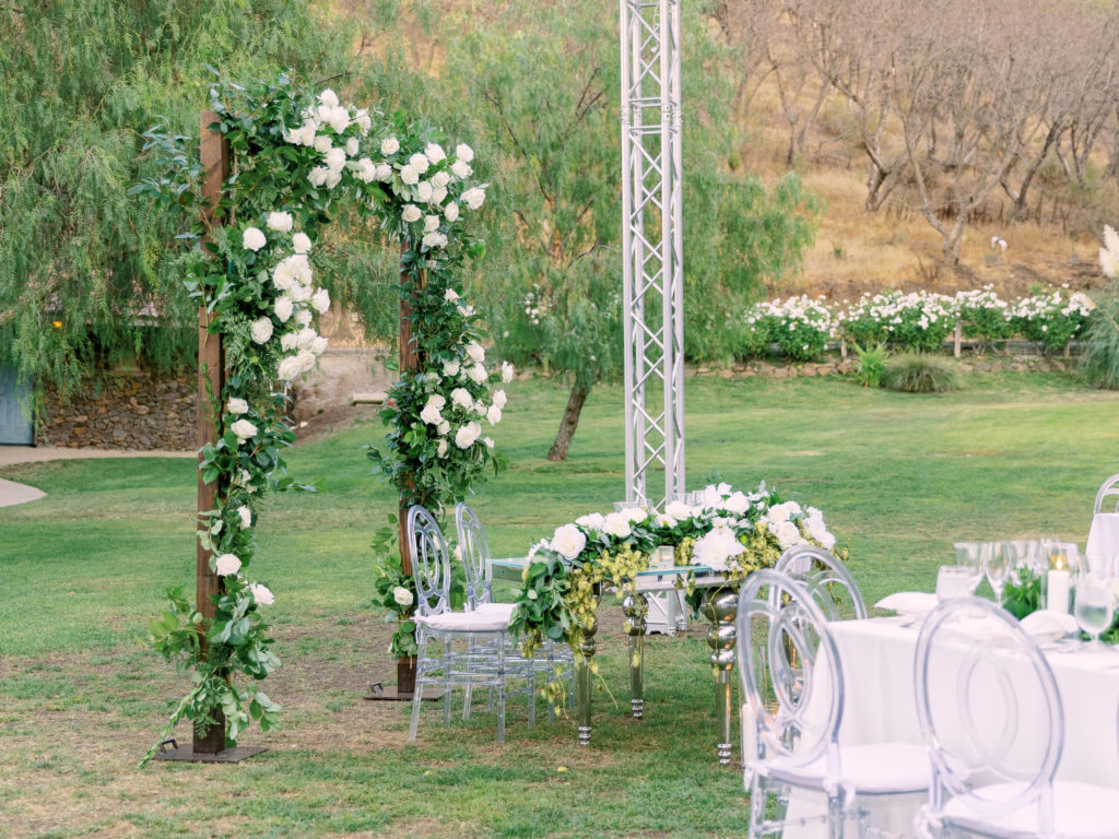 black-tie wedding reception at Saddlerock Ranch with clear reception chairs and all white rose floral centerpieces