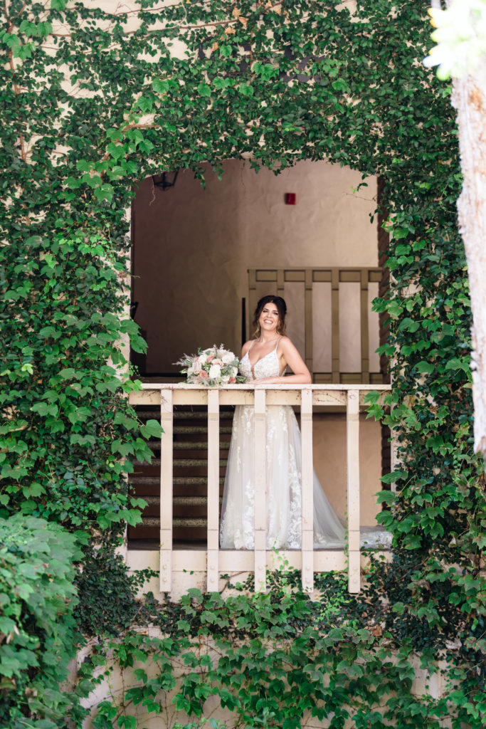 bride standing on ivy covered balcony