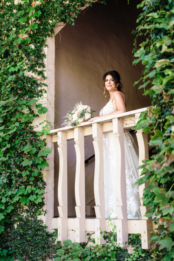 bride stands on ivy covered balcony