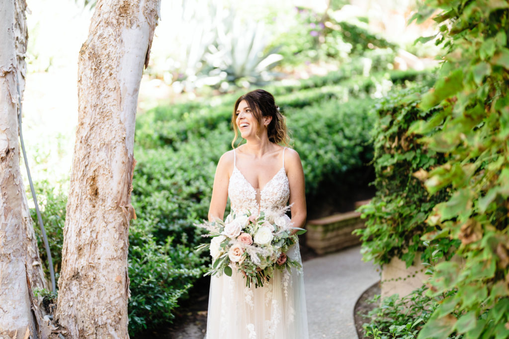 bride in floral appliqué dress stands with white and pink rose bridal bouquet
