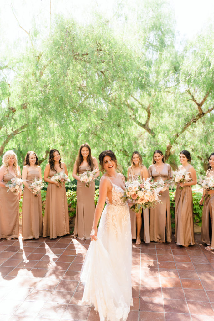 bride stands with bridesmaids in beige satin dresses
