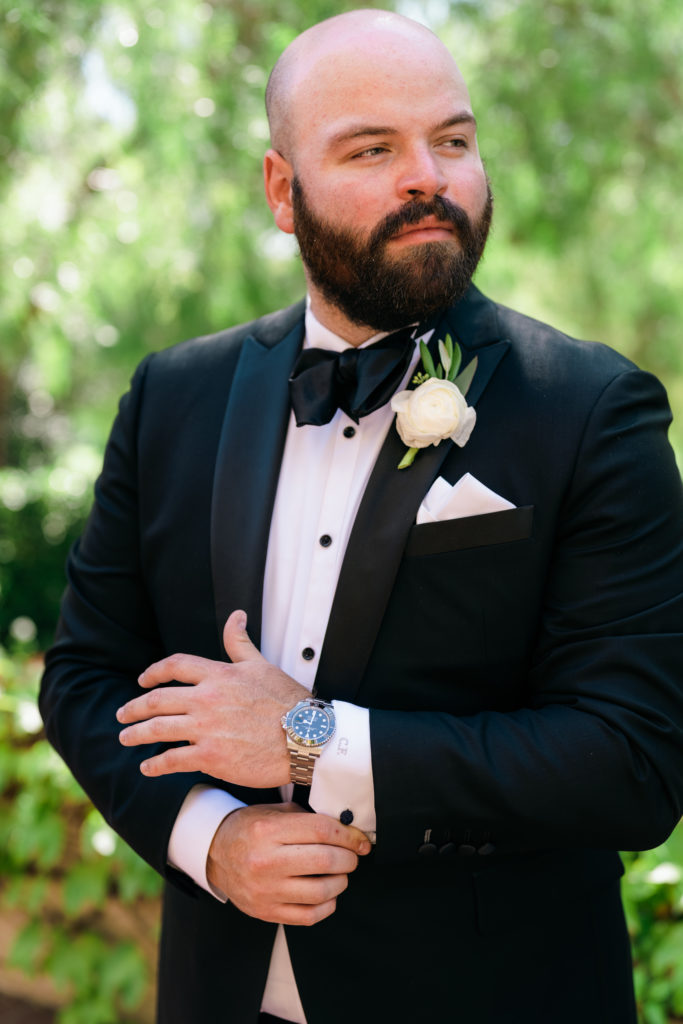 groom with black tuxedo suit and white boutonierre