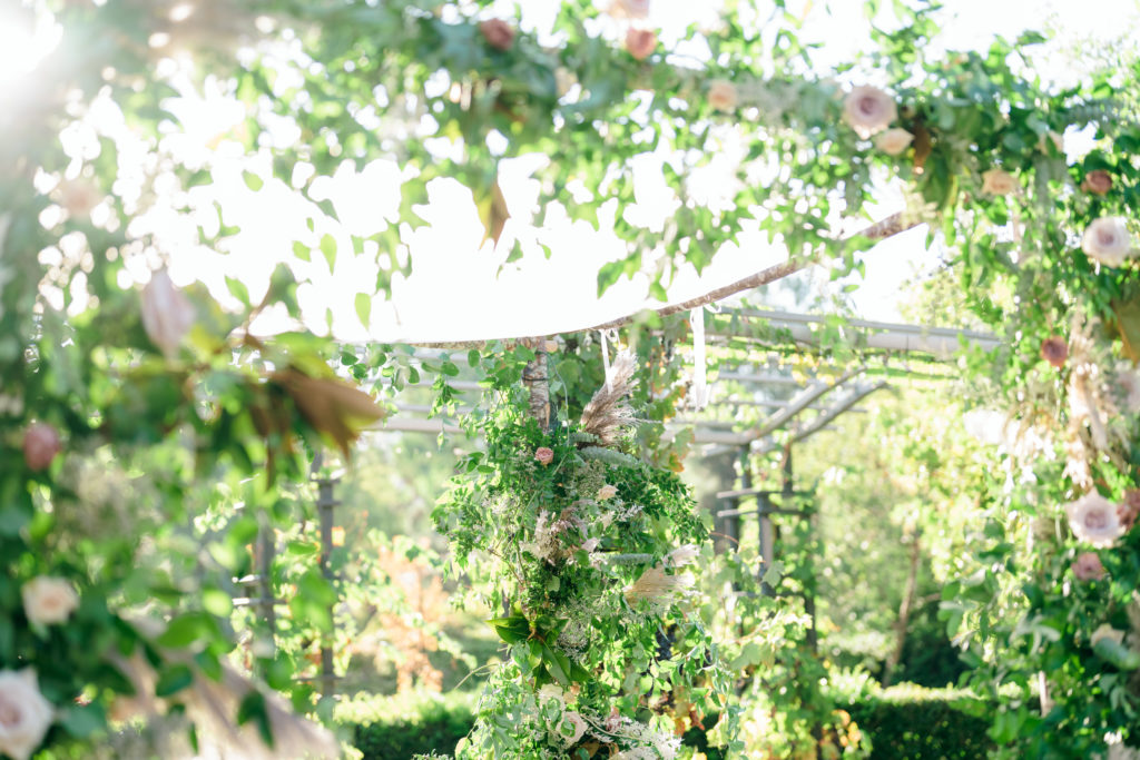 wedding ceremony chuppah wrapped in greenery and blush pink roses