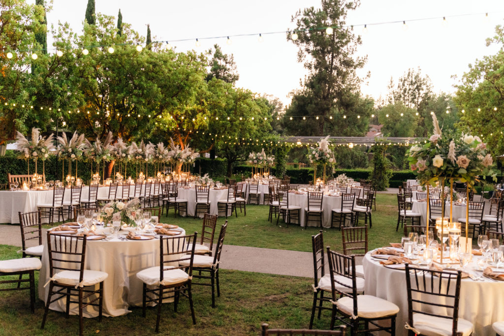 neutral palette wedding reception with tall gold floral centerpiece and wooden plate chargers