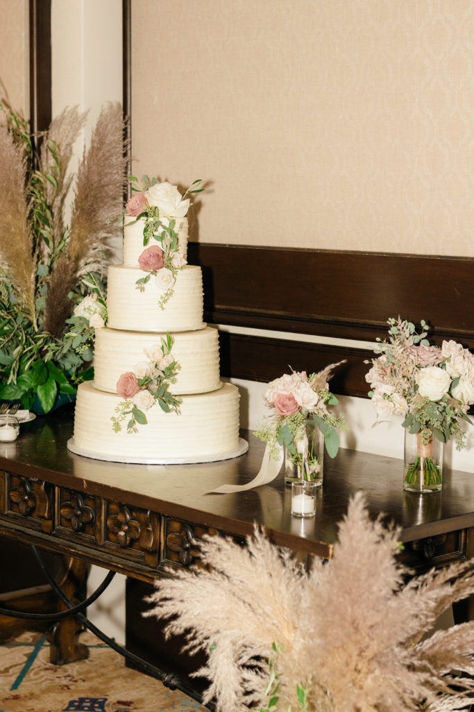 four tier white wedding cake with buttercream frosting and pink roses