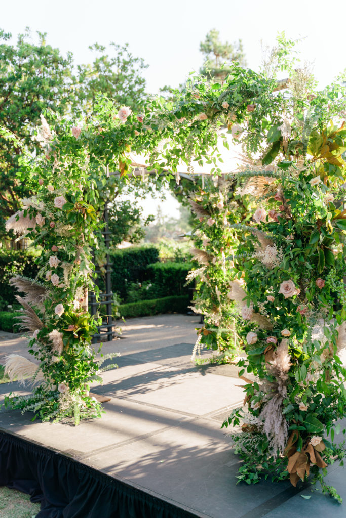 neutral color palette wedding with ceremony chuppah wrapped in greenery and blush pink roses