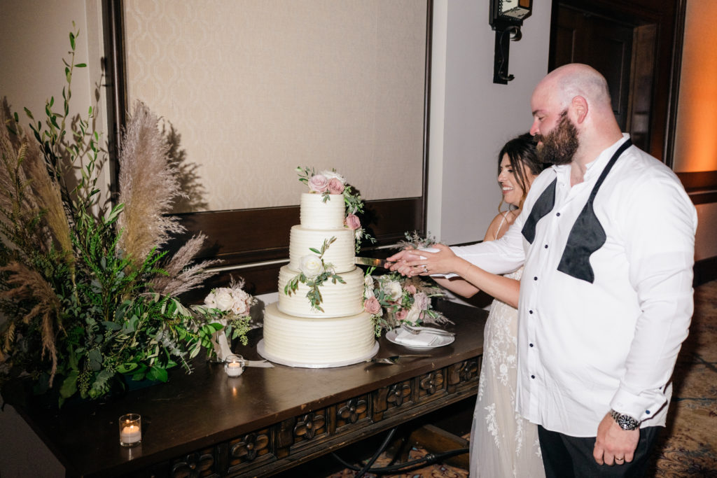bride and groom cutting a four layer cake