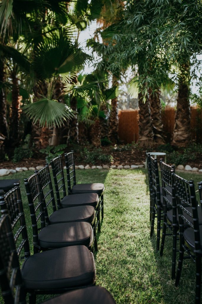 mid-century wedding ceremony with black chiavari chairs and chuppah with bright florals