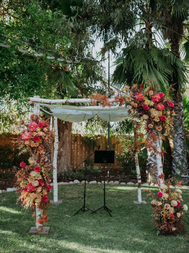 mid-century wedding ceremony with chuppah with bright florals