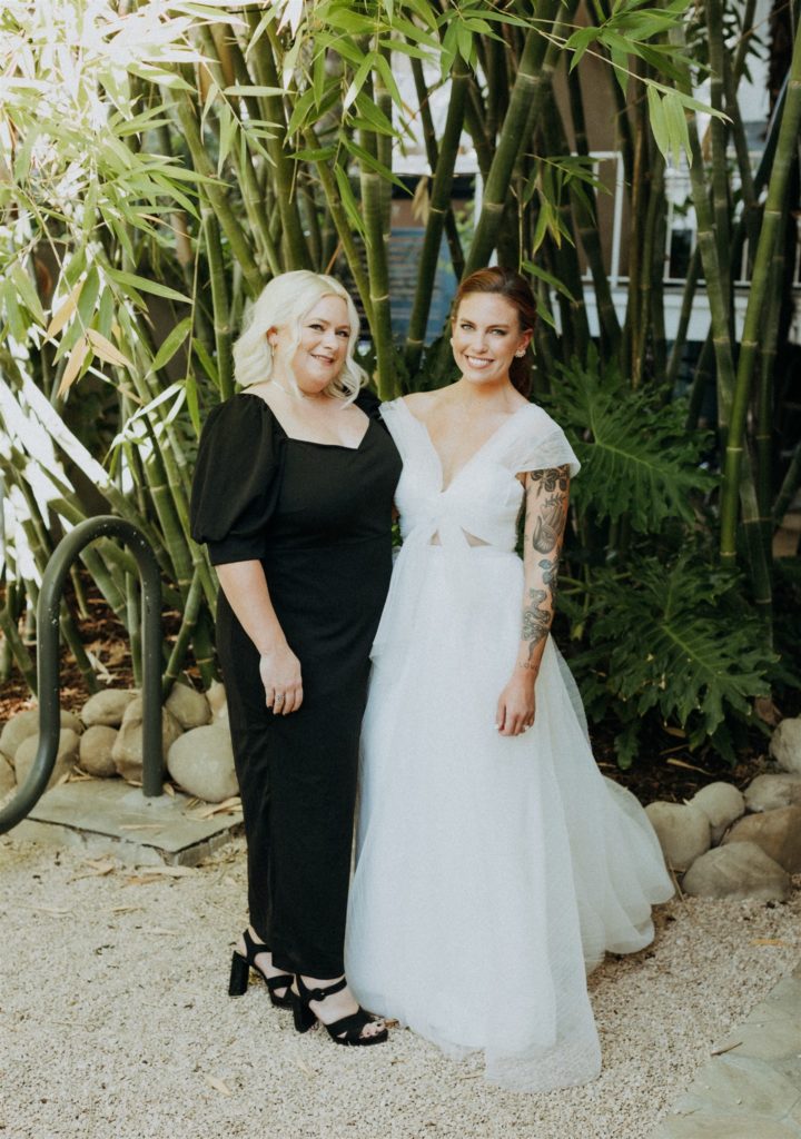 bride in modern asymmetrical dress stands with bridesmaid in black dress