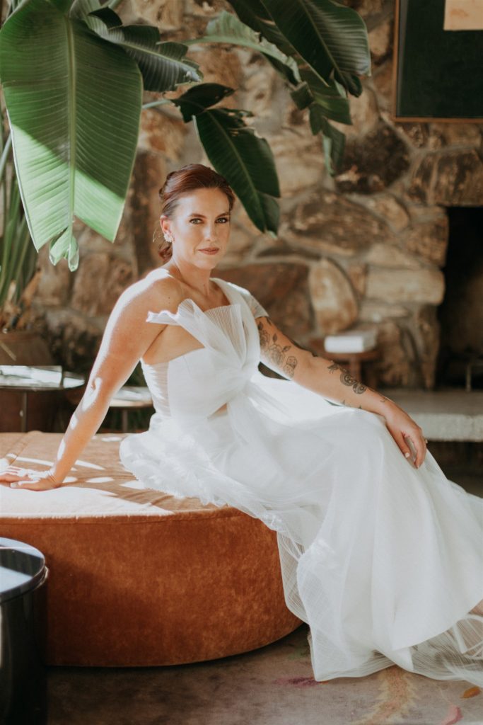 bride in modern asymmetrical dress stands in the Capri Hotel in Ojai