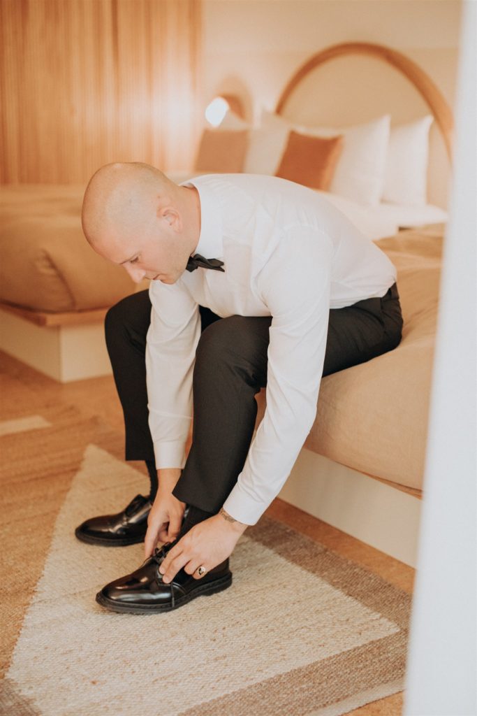 groom getting shoes on before wedding