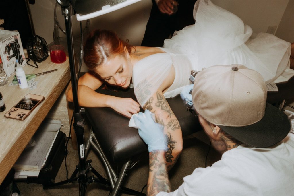 bride getting a tattoo during wedding reception 