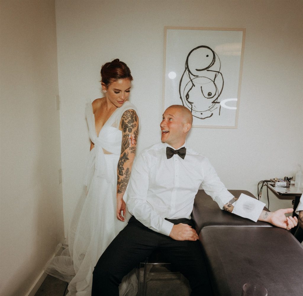 bride and groom show off matching tattoos during wedding reception 