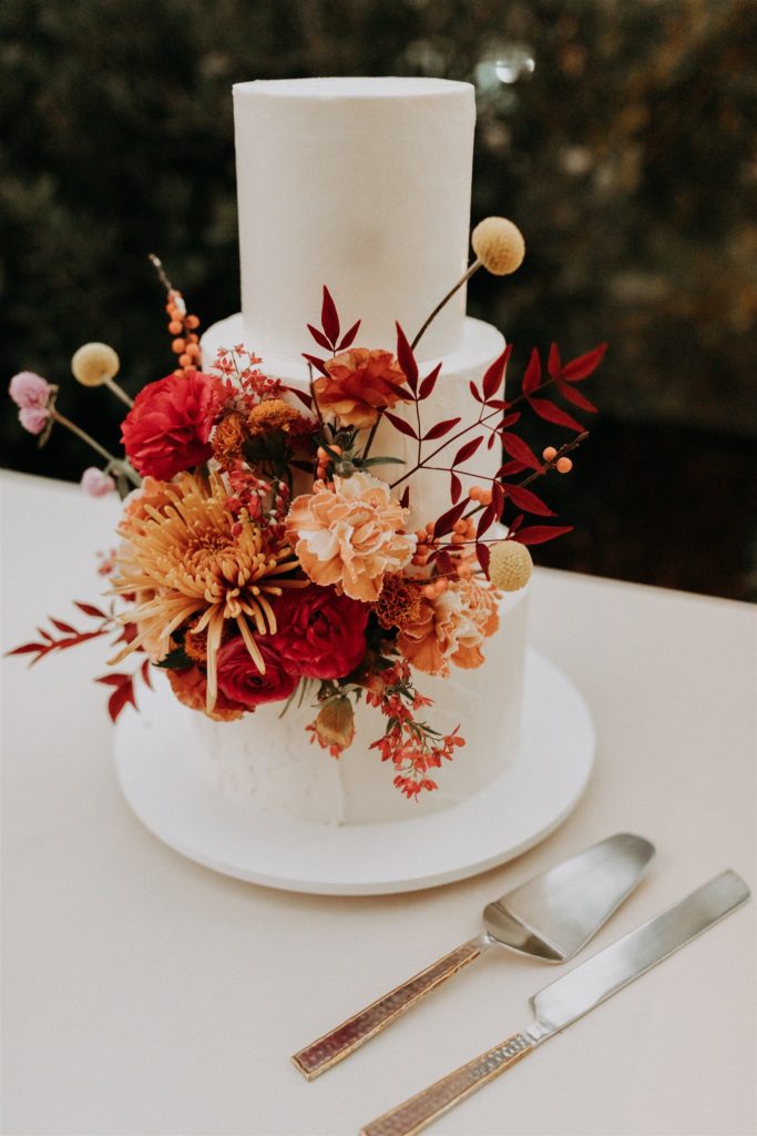 mid-century inspired three tier wedding cake with red and orange florals