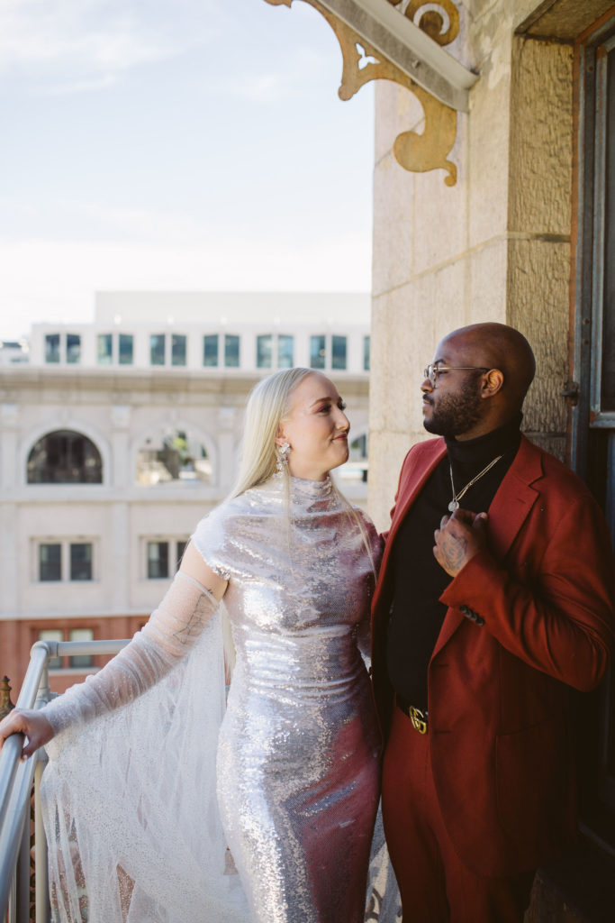 bride in silver wedding dress and groom in red suit get ready together for their disco inspired wedding in DTLA