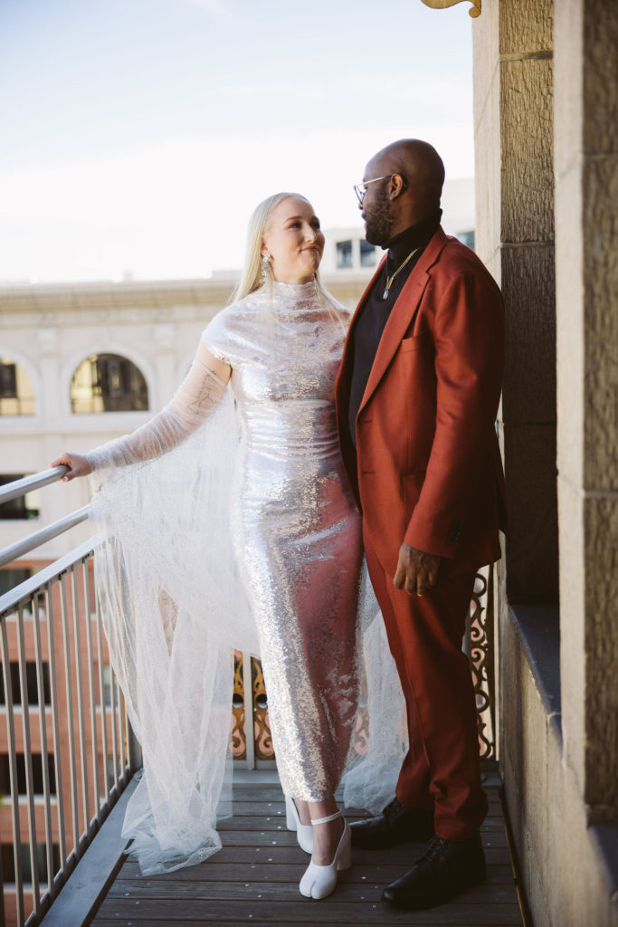 bride in silver wedding dress and groom in red suit get ready together for their disco inspired wedding in DTLA
