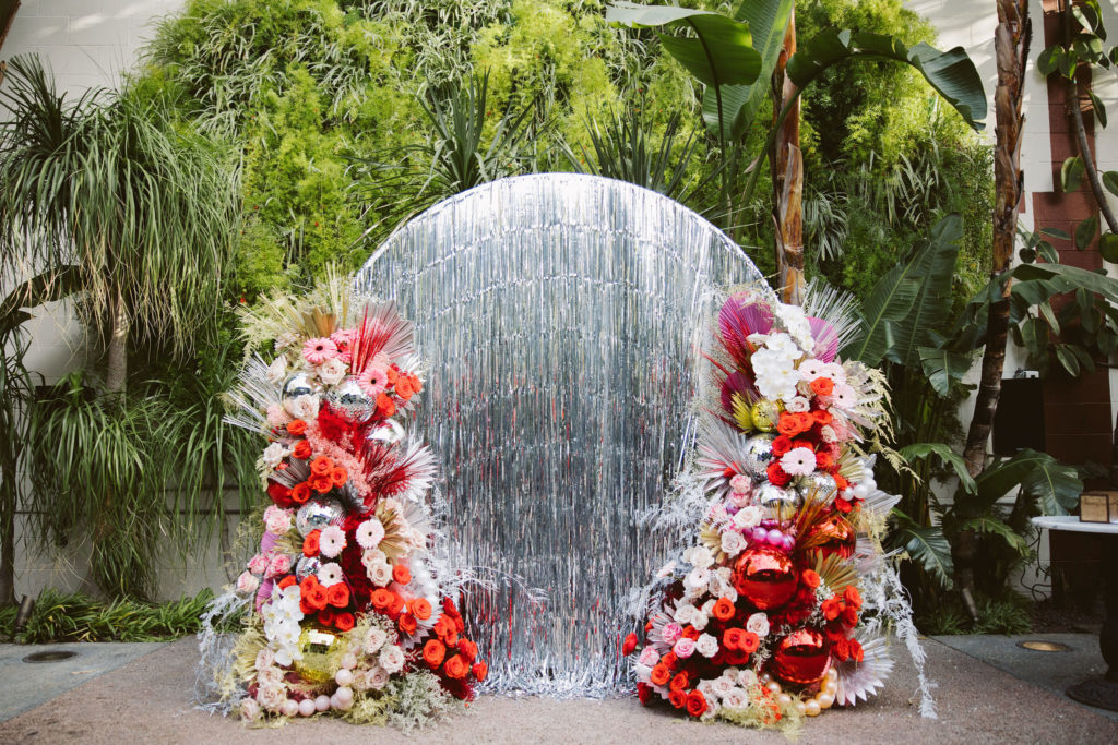 silver tinsel wedding circle with pink and red floral arches with disco balls