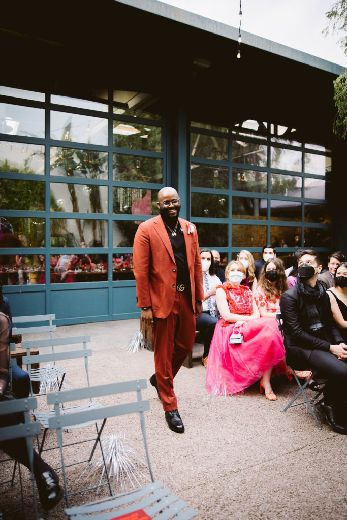 groom in red suit walks down the aisle