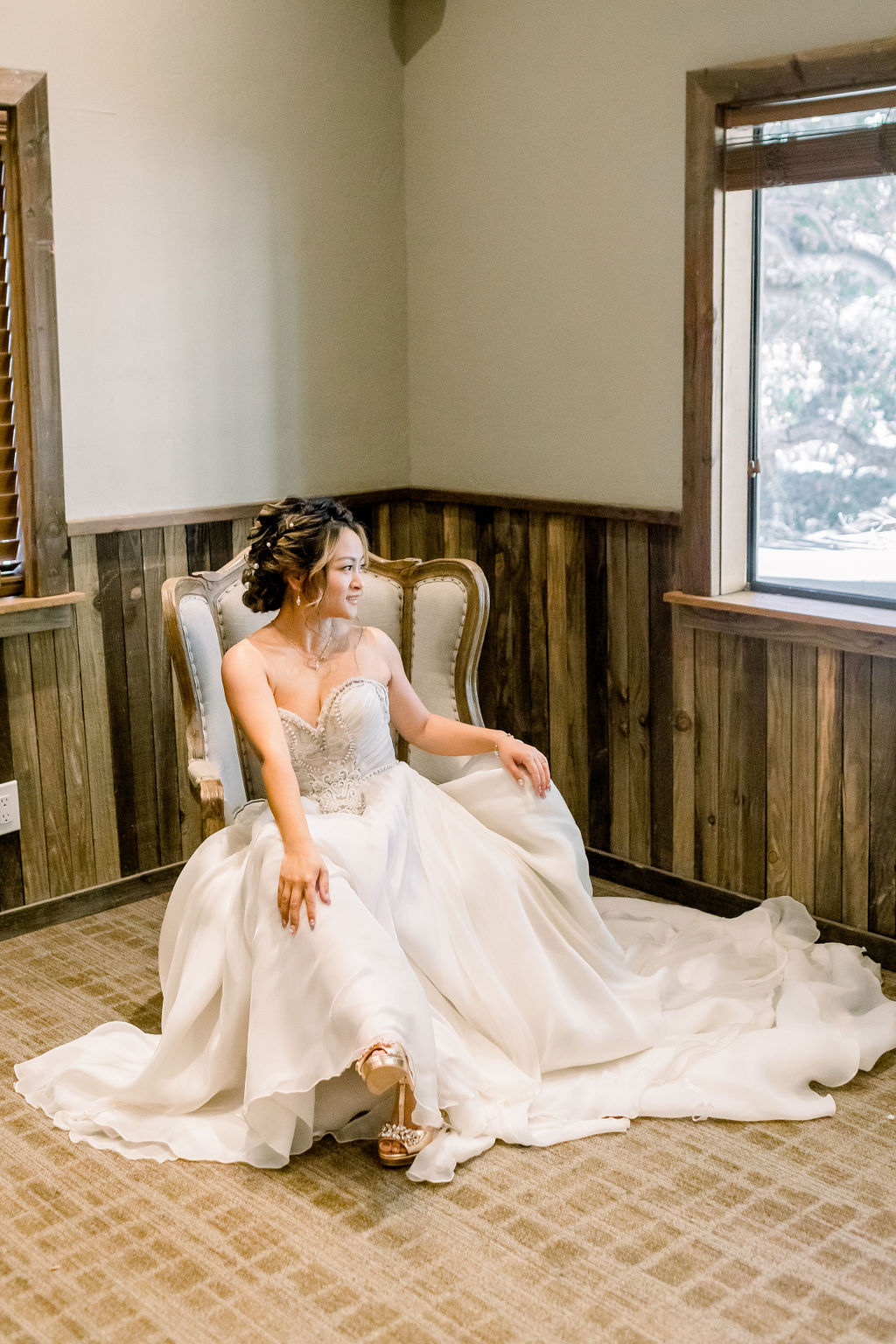 bride in embellished strapless chiffon wedding dress sits on chair