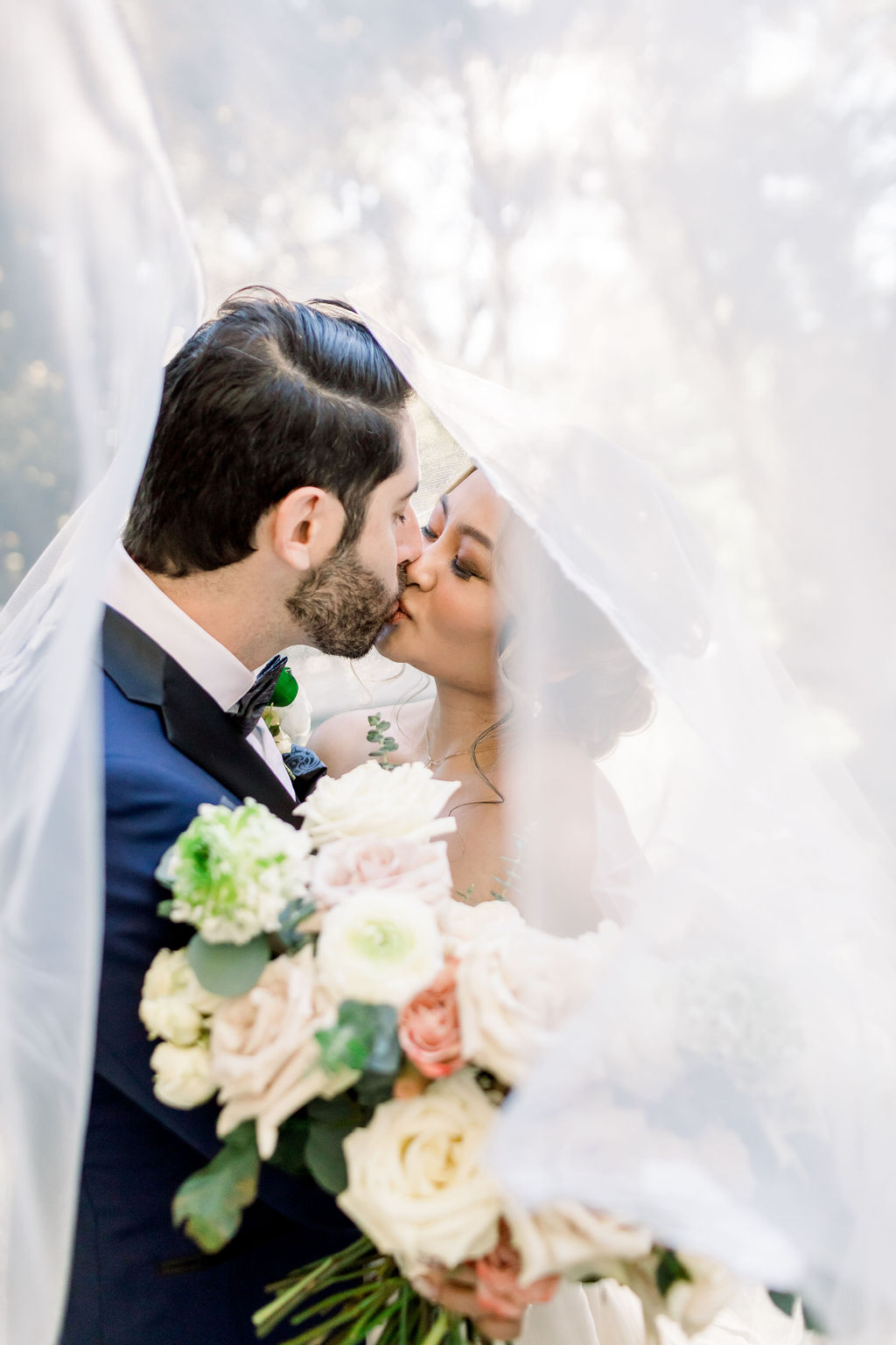 bride and groom take portraits under wedding veil 