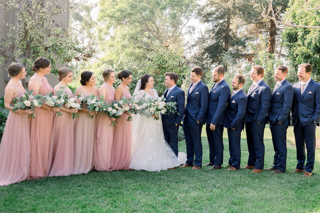 wedding party photo with pink bridesmaid dresses and blue groomsmen suits with floral ties