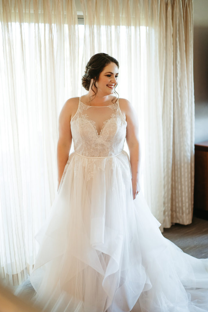 bride wearing tiered ballgown wedding dress with lace detail on sweetheart neckline and champagne silk lining